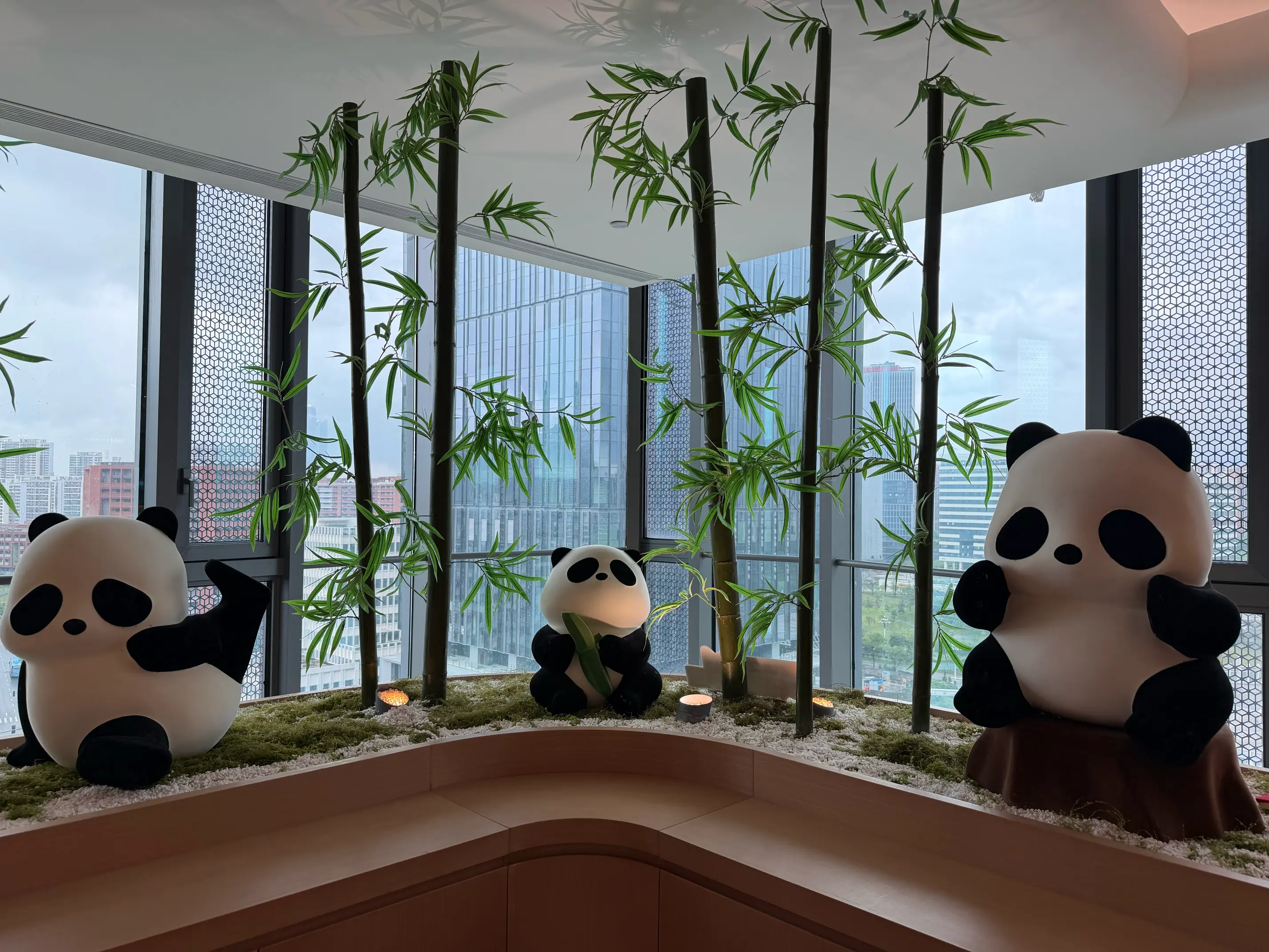 Panda figures among bamboo by large office windows